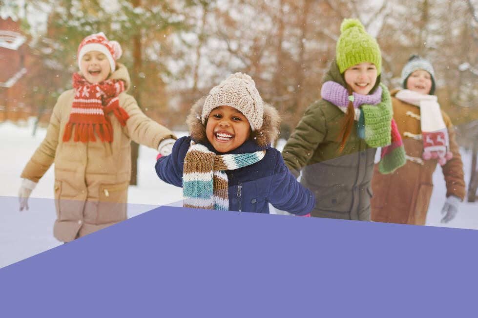 Four children playing outside in the snow and smiling at the camera